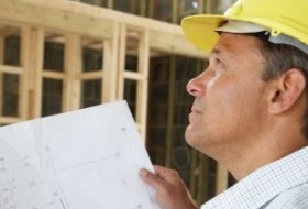 Man in construction hat reviewing blueprints.