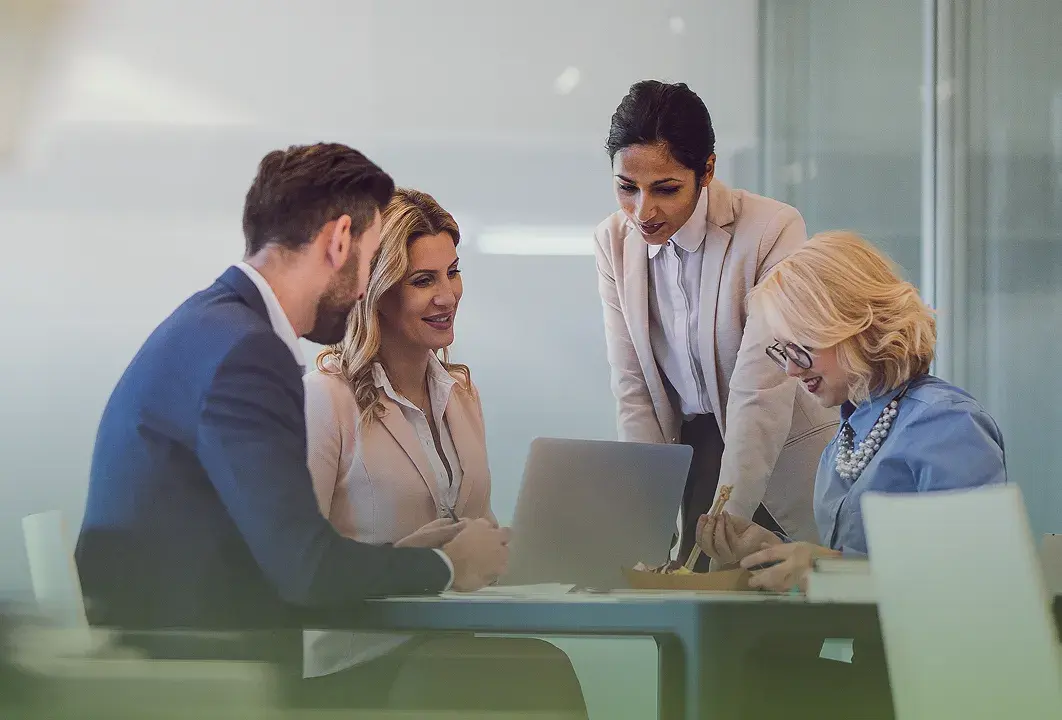 A CDB team collaborating around a laptop in a conference room