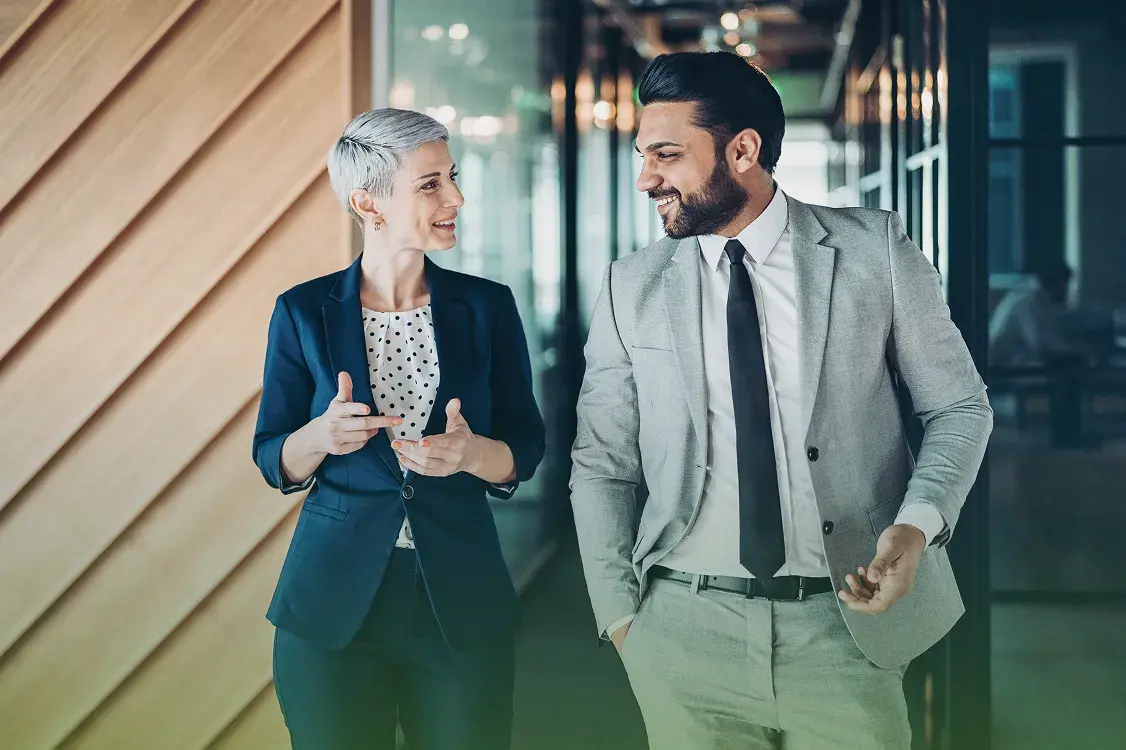Two business colleagues walking and talking together in a modern office