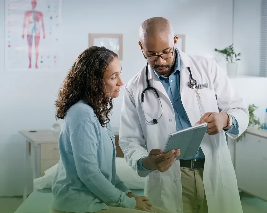 A doctor reviewing care details with a patient on a tablet